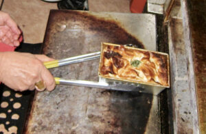 Removing baked spanakopita from oven at Cafe Nova