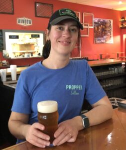 Abbey Spencer holding a beer inside Third Wheel Brewing