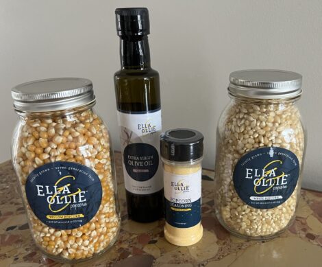 Two jars of Ella and Ollie popcorn with a bottle of seasoning salt and a bottle of oil.