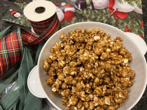 A container of caramel corn and ribbons preparing to give as a gift.