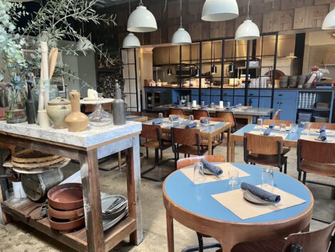 View of inside Spartina with open kitchen and blue, wood trimmed tables.