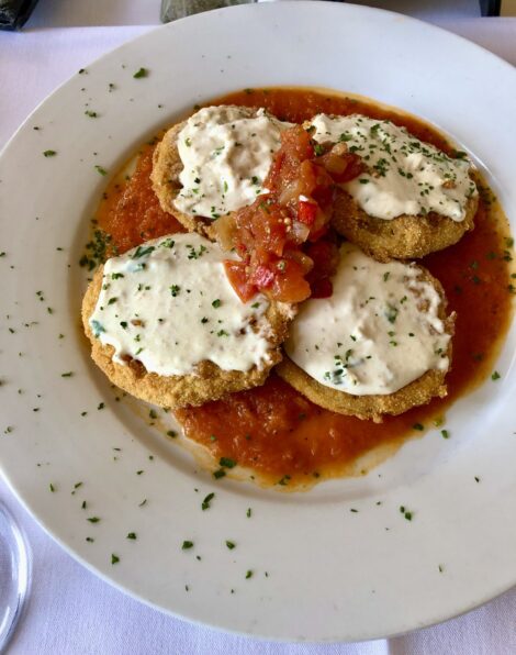 A plate of fried eggplant topped with cheese sauce.