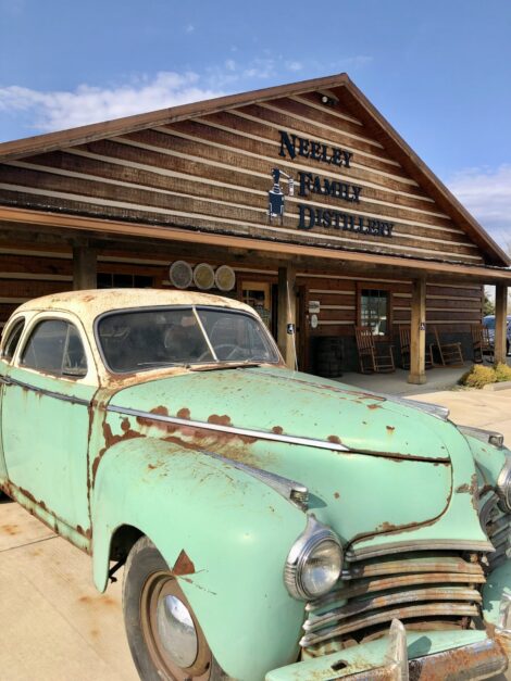 The Neeley Family Distillery with an old car in front.