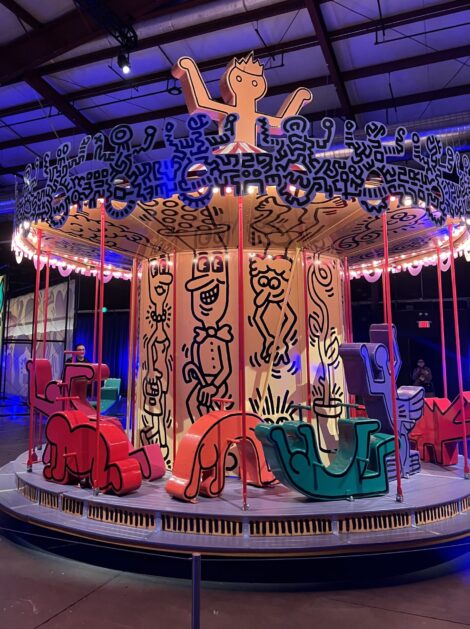 Cartoon figures showcase a carousel painted by artist Keith Haring.